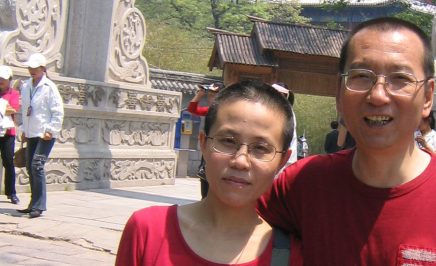 Chinese artist Liu Xia with her late husband and Nobel laureate Liu Xiaobo. Both are looking at the camera and wearing red tshirts. The man is smiling.