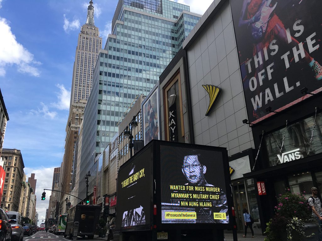 Wanted poster of Myanmar's top military general, Min Aung Hlaing, on a billboard in New York. Backdrop of iconic New York skyscrapers.