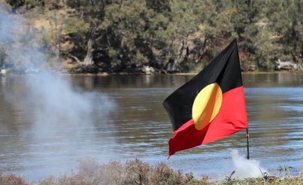 Aboriginal flag fluttering in the breeze with a river in the background