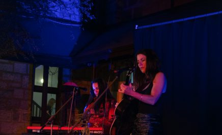 Lucy Peach playing guitar and singing on stage at Beats for Bravery