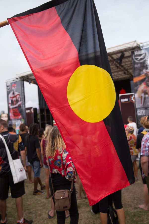 The Aboriginal Flag being flown at Yabun Festival 2018, in the distance is a stage and festival participants