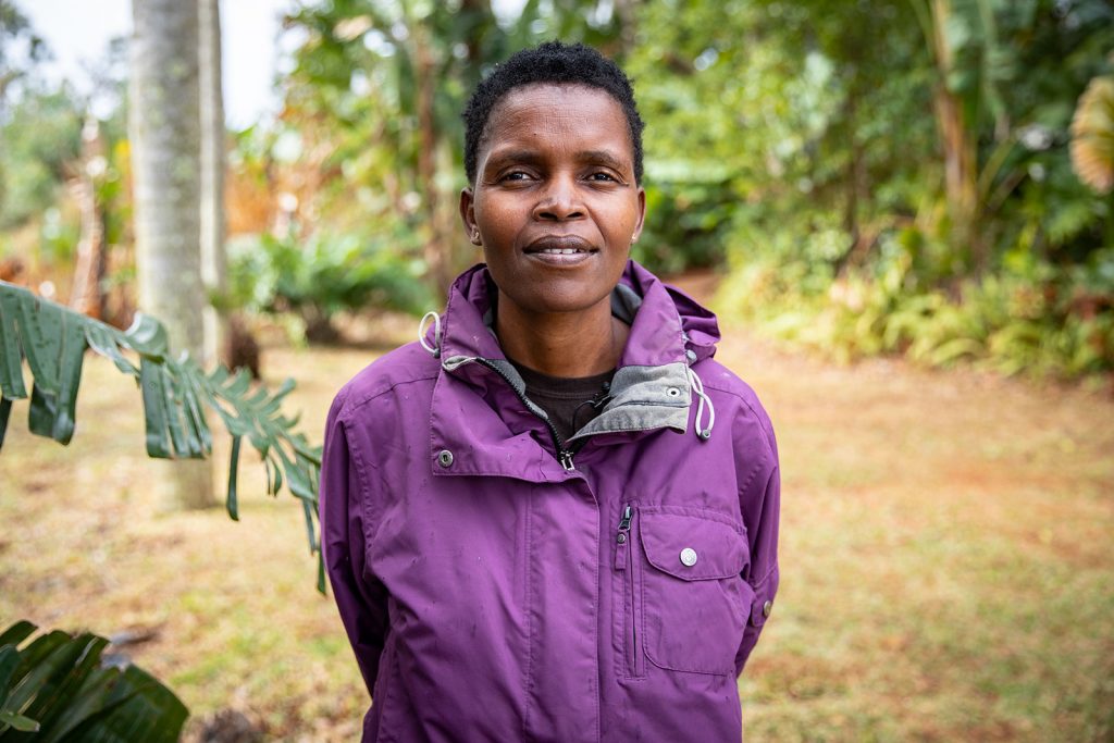 A woman wearing a purple coat smiles towards the camera.