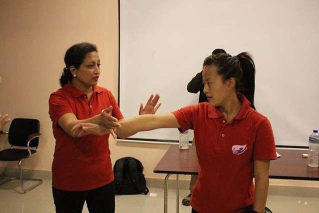 A women in a red t-shirt is teaching self-defence another woman in a red t-shirt.