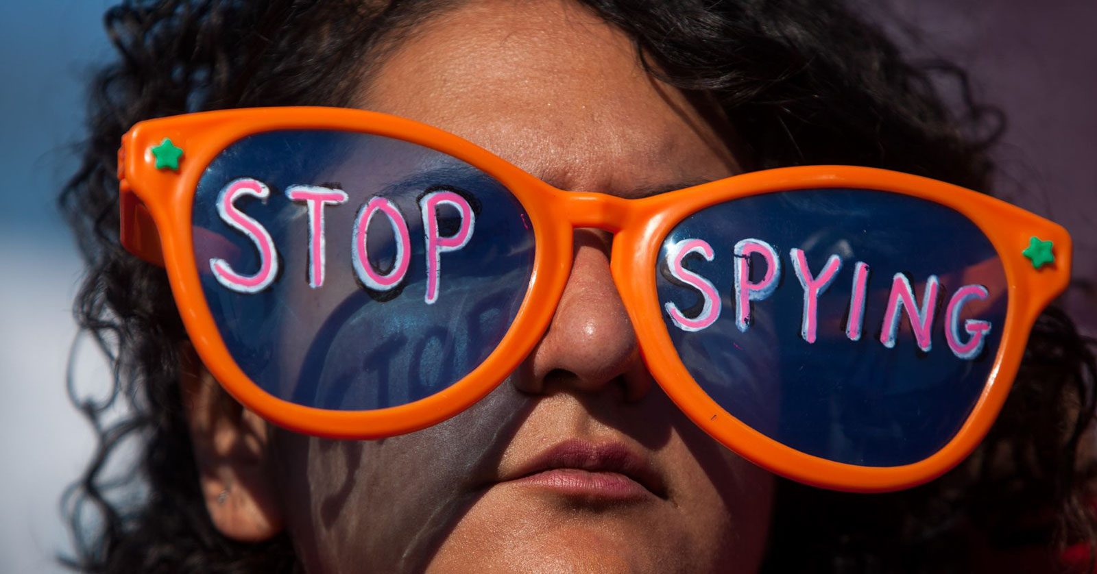 A woman wearing a pair of glasses with 'Stop spying' written on the lenses.