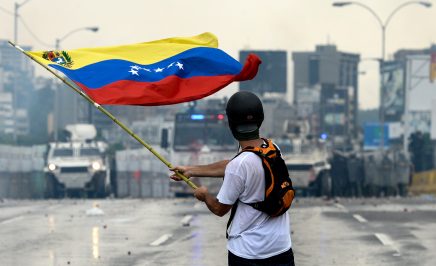 A Venezuelan opposition demonstrator waves a flag at the riot police in a clash during a protest against President Nicolas Maduro, in Caracas in 2017.