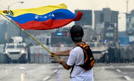 A Venezuelan opposition demonstrator waves a flag at the riot police in a clash during a protest against President Nicolas Maduro, in Caracas in 2017