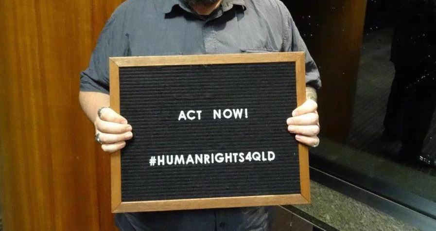 A person holding up an act now sign
