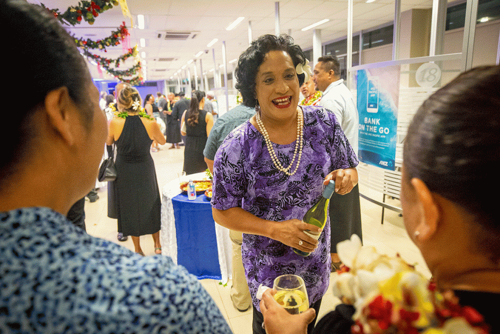 A woman in a purple dress talks to two other women at a party.