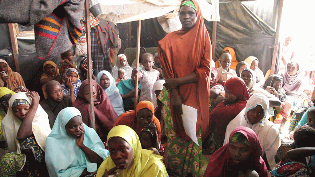 A group of women wearing brightly coloured clothes and headscarves look towards the camera.