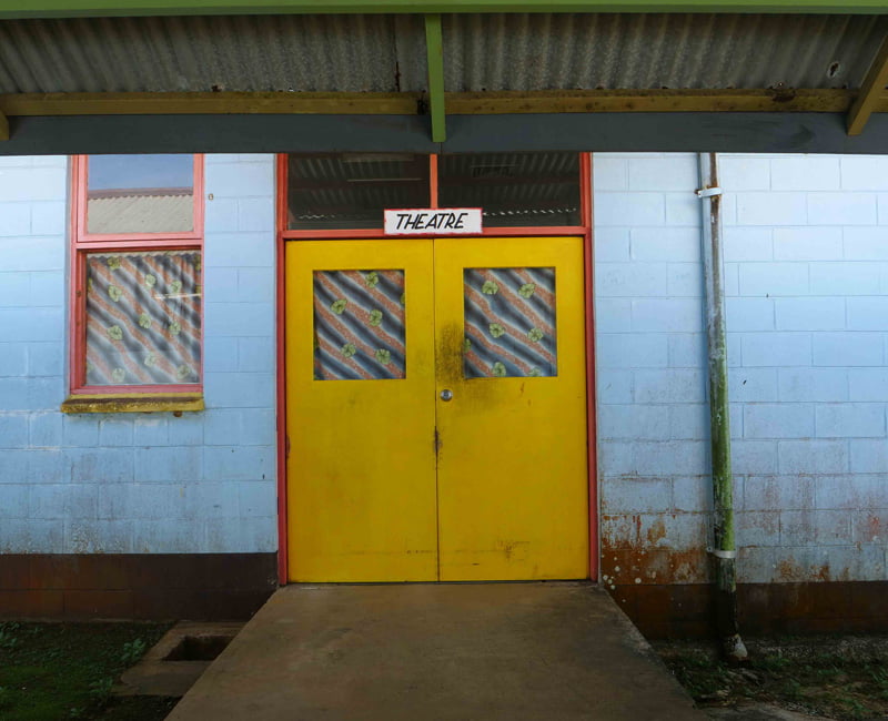 Yellow doors on a rundown building, with a sign 'theatre' above it