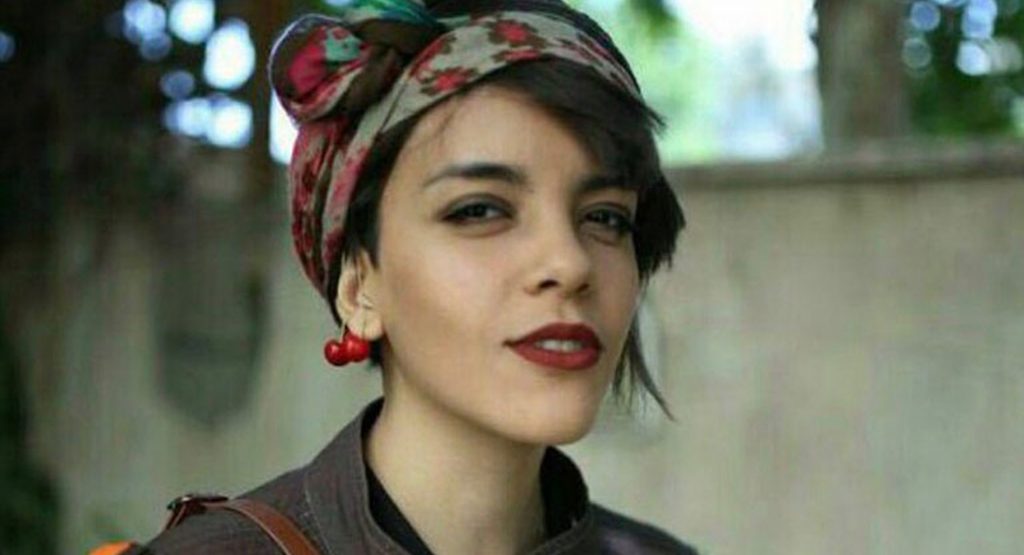 A young woman wearing stylish earrings and a colourful headband, smiling into the camera