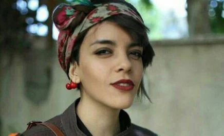 A young woman wearing stylish earrings and a colourful headband, smiling into the camera