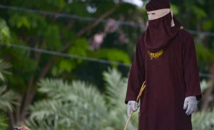 Sharia police waiting and holding a cane