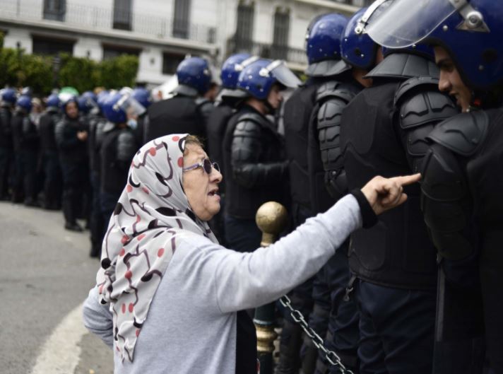 An elderly Algerian woman talks to a member of the security forces cordoning off a protest area during an anti-establishment demonstration in the capital, Algiers