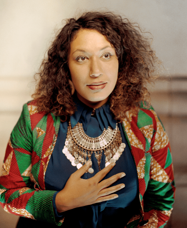 Marcelle Partouche, Community welfare worker and artist from Canada, wears a colourful jacket and holds her hand over her chest at The Peoples' Summit on Climate, Rights and Human Survival, New York, USA, 18 September, 2019.