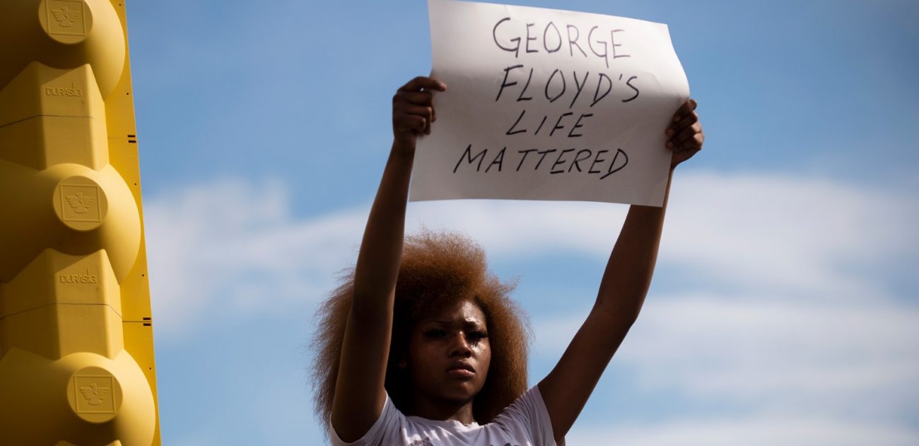 A women in a white t shit hold a sign saying 