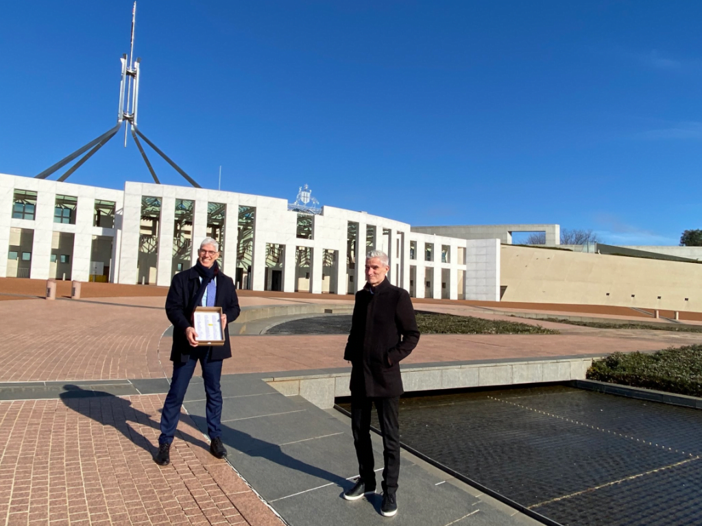 Craig Foster and Dr Graham Thom stand in front of Australian Parliament with petitions