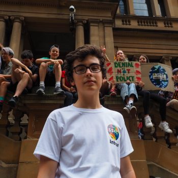 A portrait of School Strike for Climate actvist Ambrose Hayes, with other strikers sitting behind him.