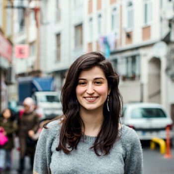 A portrait of Refugee Activist Samah Shda, smiling in the street.