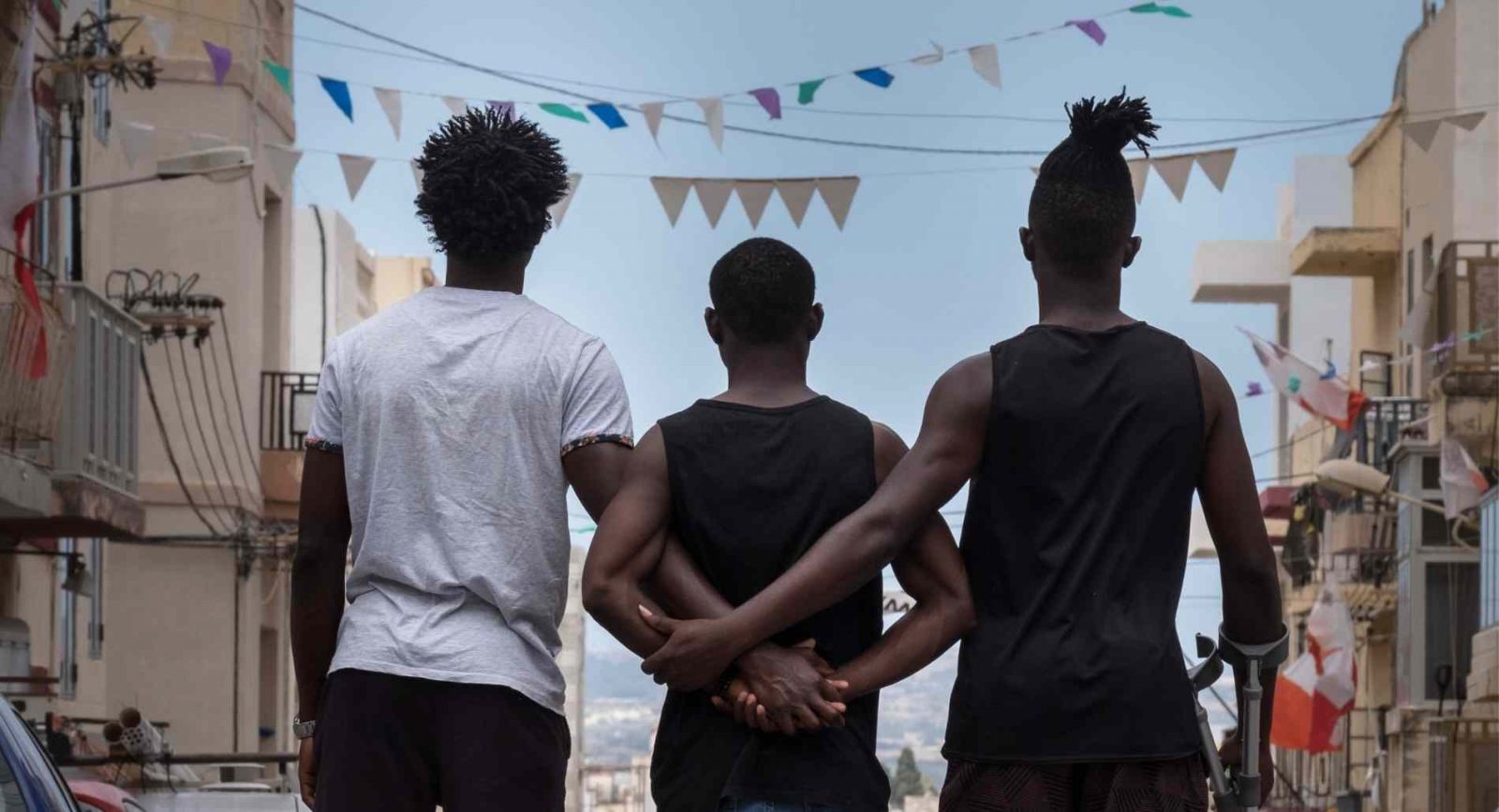 The El Hiblu 3 stand shoulder to shoulder linking arms in a Maltese street.