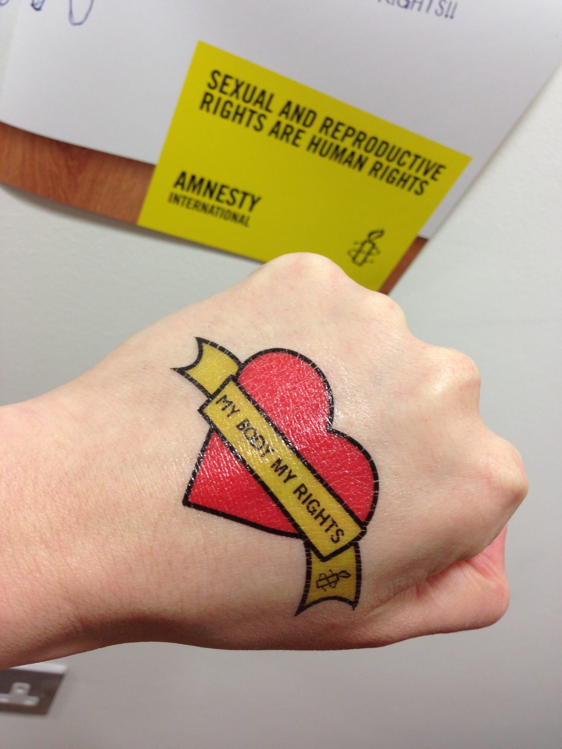 A hand with a love heart tattoo and the words "my body, my rights" and the Amnesty candle logo.
