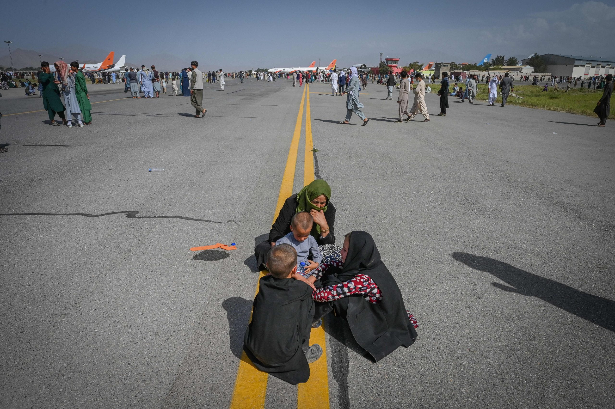 Afghan family huddled in the middle of the airport tarmac.
