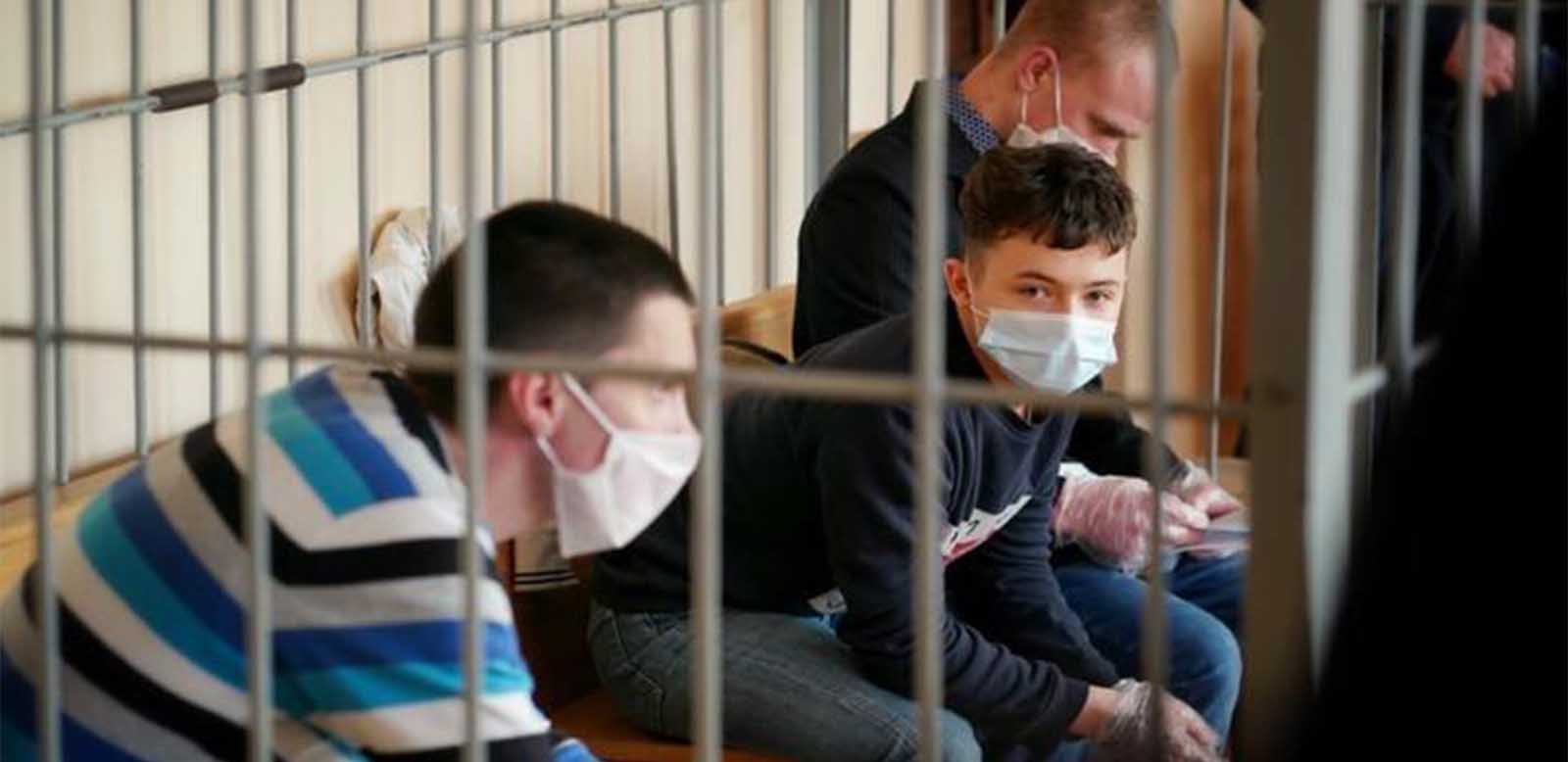 image of a young boy wearing a mask behind bars
