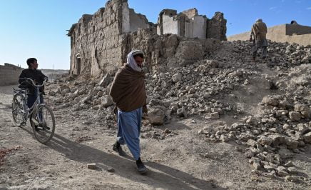 people walk past the ruins of destroyed houses in Arzo village on the outskirts of Ghazni. - Rural areas such as Arzo bore the brunt of the two-decade conflict that saw Taliban insurgents face US, NATO and Afghan forces, with civilian casualties inflicted by both sides.